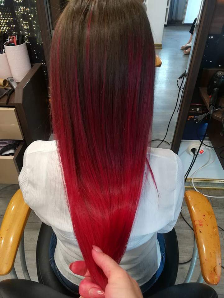 Vivid color — bold magenta-red peekaboo color underneath natural brunette on long straight hair, back view at Divine Retreat salon