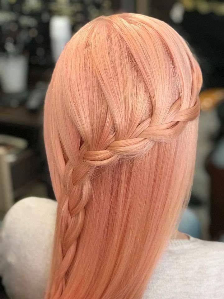 Vivid color and styling — pastel peach-pink all-over color with waterfall braid on long silky straight hair, back view at Divine Retreat salon