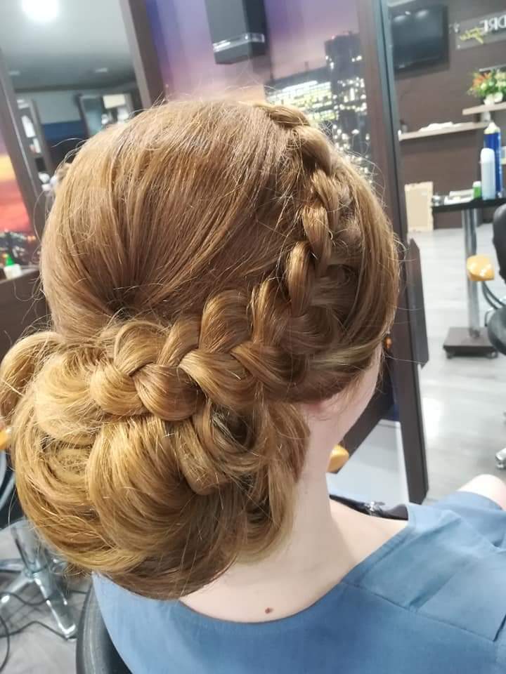 Braided updo — Dutch braid crown swept into a textured low bun on warm light brown hair, back view at Divine Retreat salon