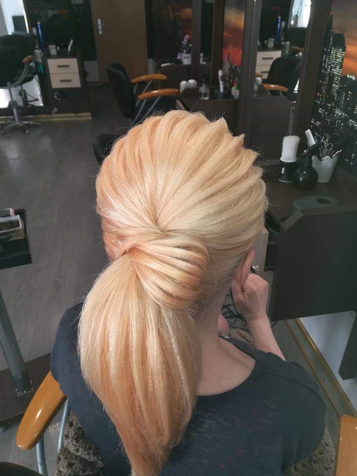 Elegant ponytail styling — twisted low ponytail on warm strawberry blonde hair, back view at Divine Retreat salon