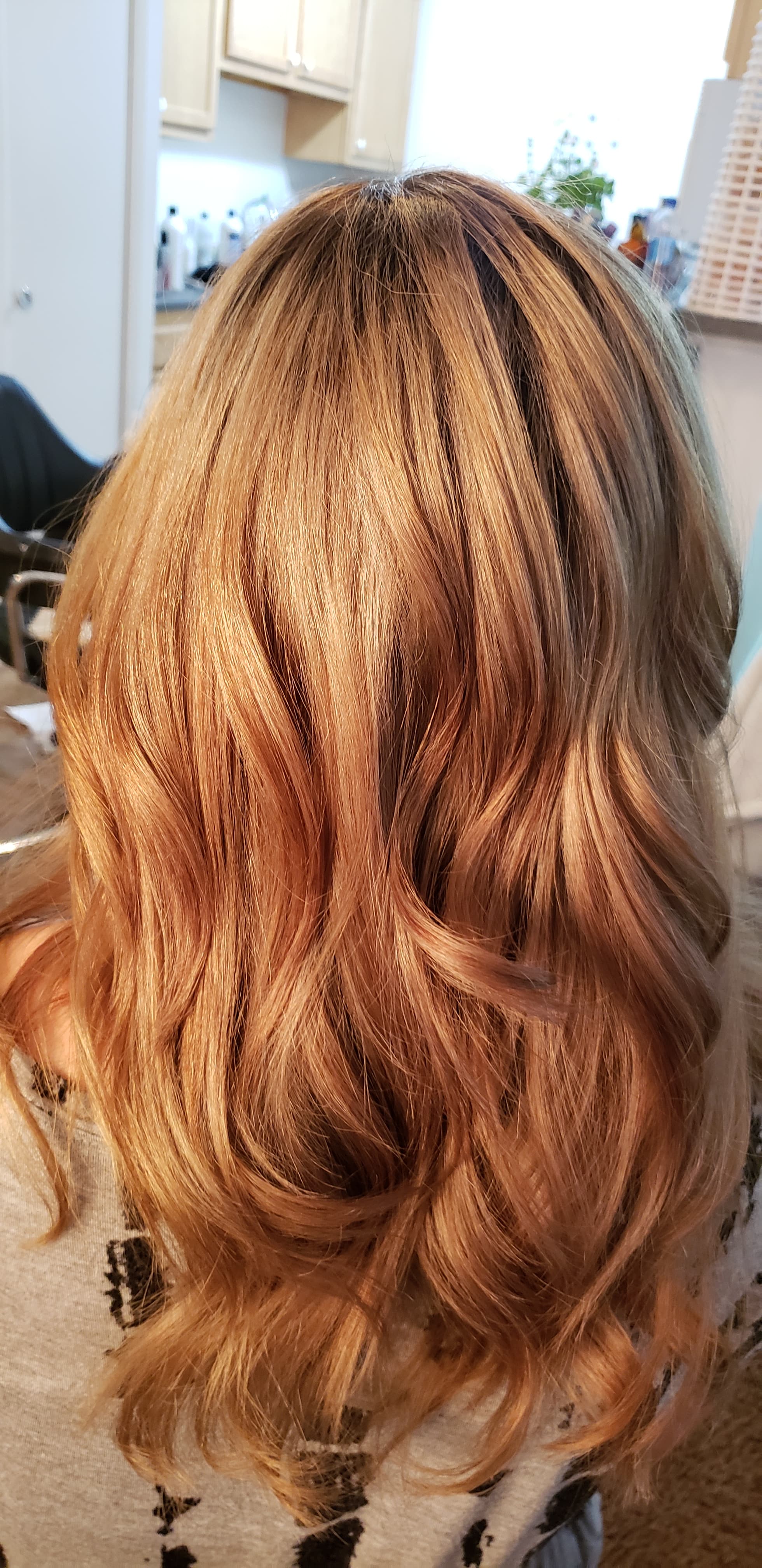 Copper color transformation — warm strawberry copper all-over color with soft bouncy curls on medium-length hair, back view at Divine Retreat salon