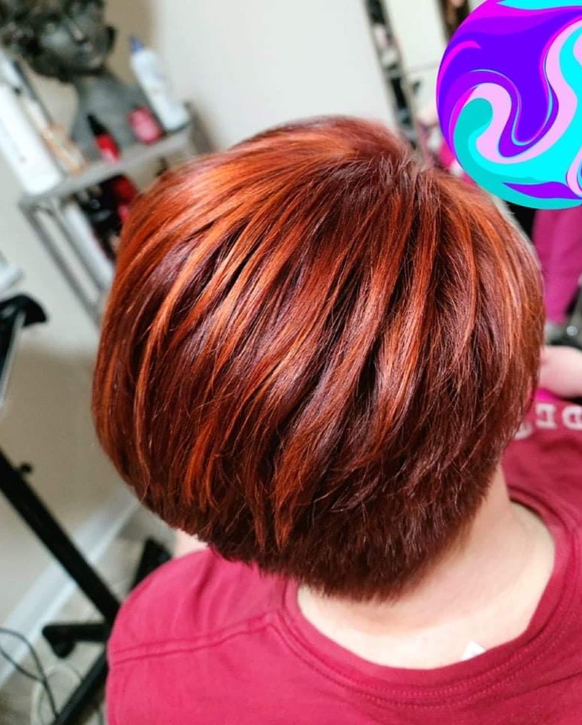 Vivid copper red color — rich auburn-to-copper all-over color with dimensional highlights on a layered stacked bob, top-down back view at Divine Retreat salon