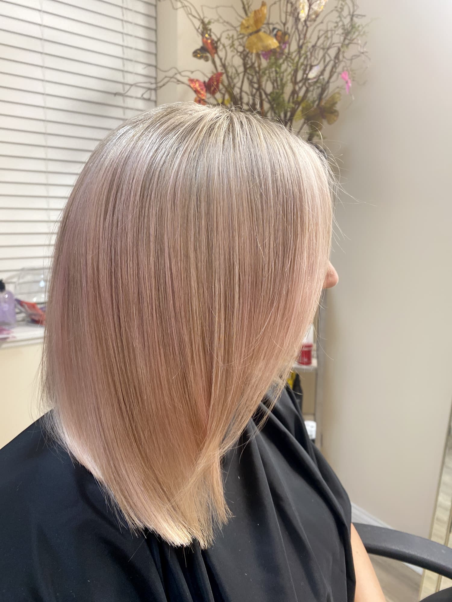 Rose gold blonde color — soft pastel pink-toned blonde on a sleek medium-length lob with smooth blowout finish, side profile view at Divine Retreat salon