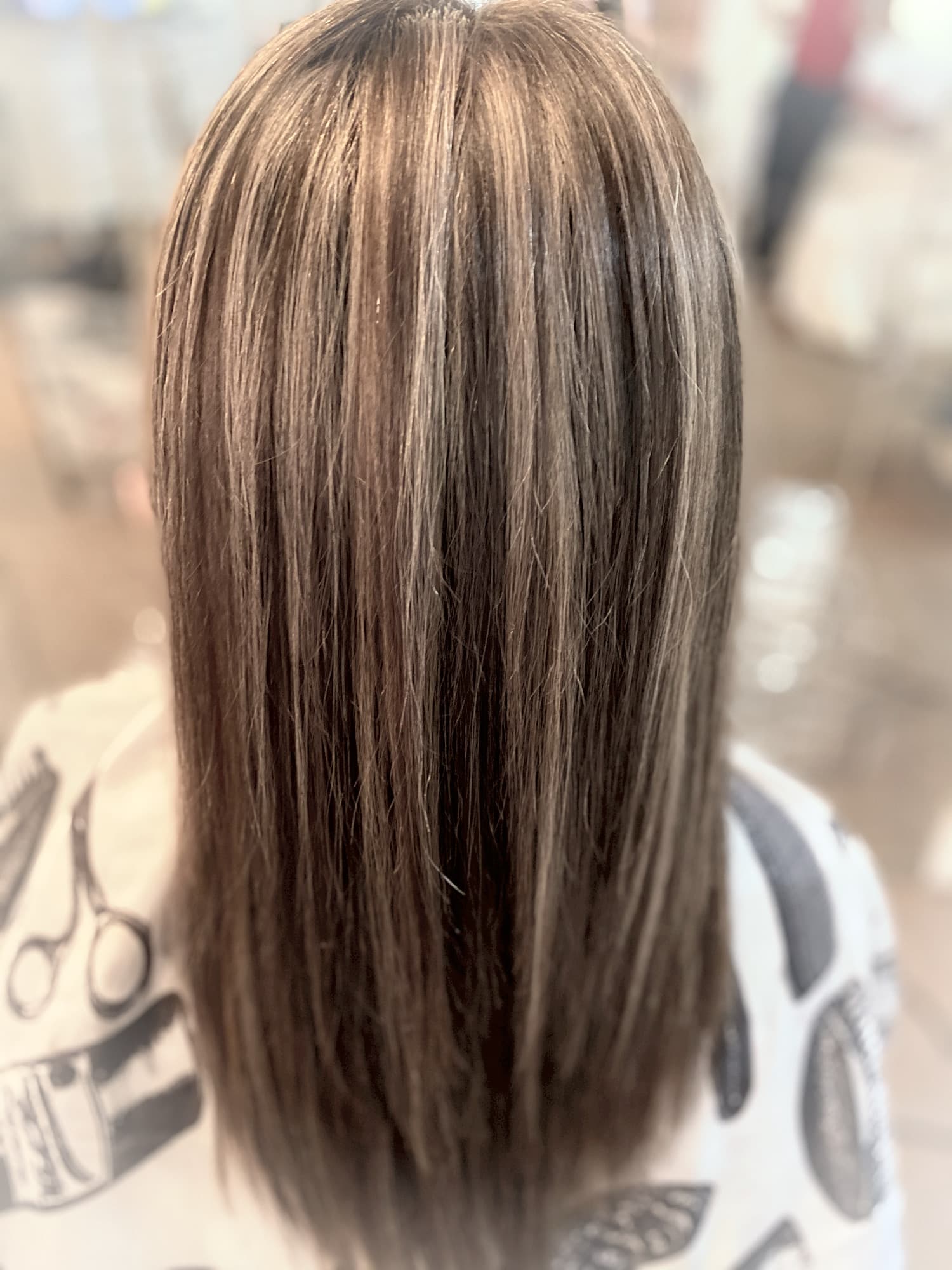 Subtle highlights — natural-looking caramel and ash highlights blended into medium brunette hair on a straight medium-length cut, back view at Divine Retreat salon