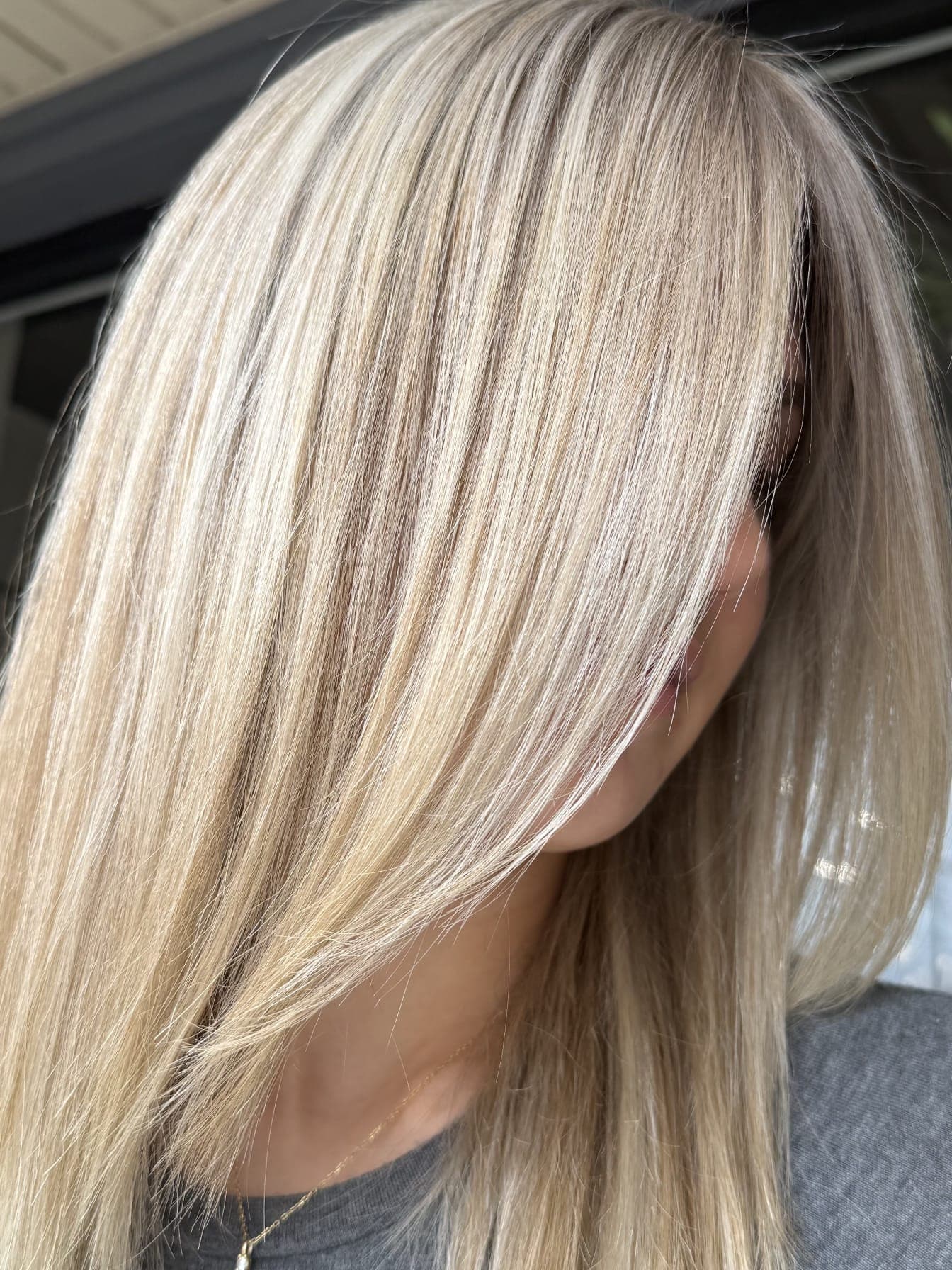 Platinum blonde highlights — icy cool-toned blonde with subtle lowlights on long sleek hair, side profile view at Divine Retreat salon