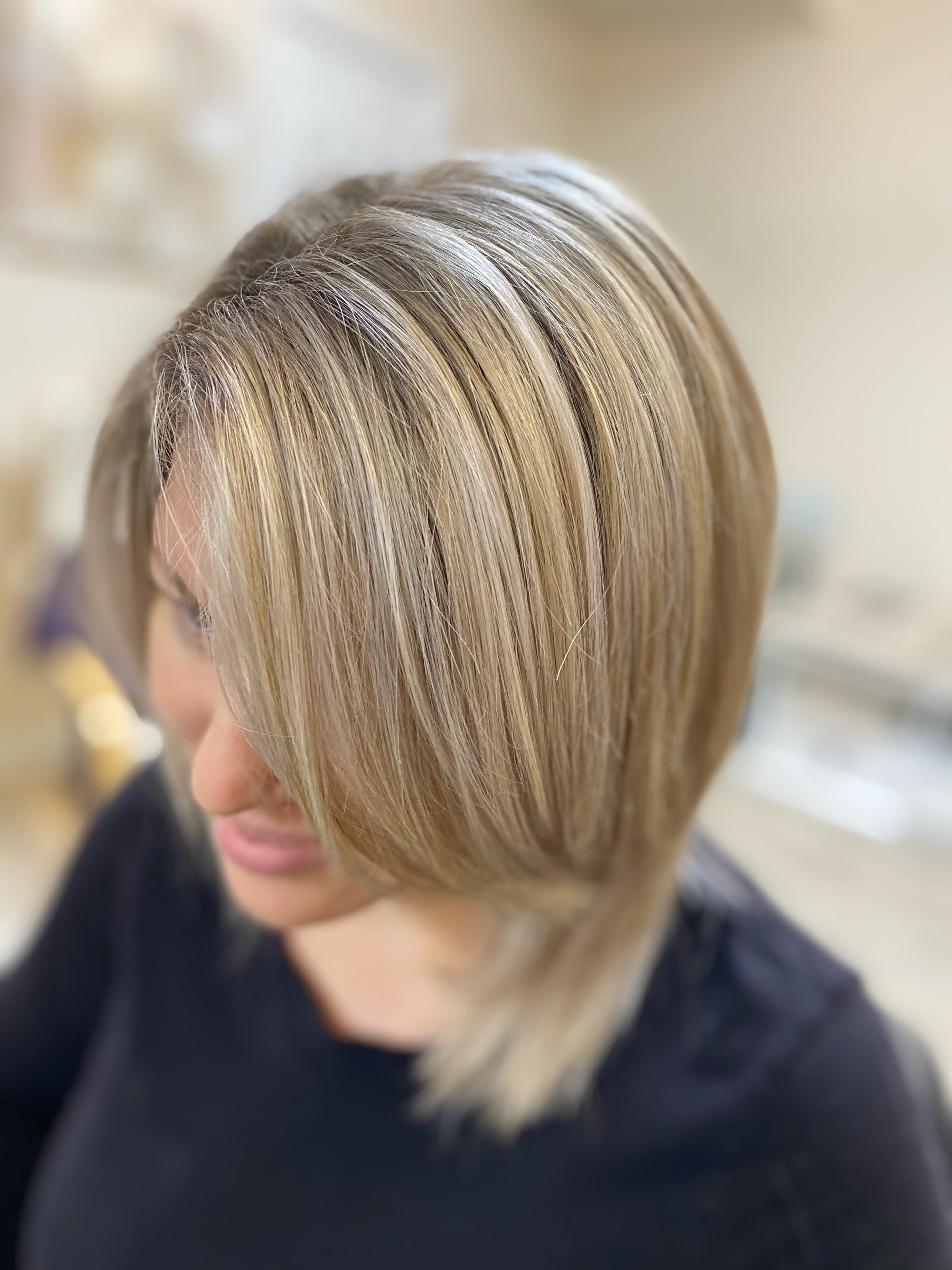 Dimensional highlights — warm honey and caramel highlights blended into a sandy blonde short bob, side profile view at Divine Retreat salon