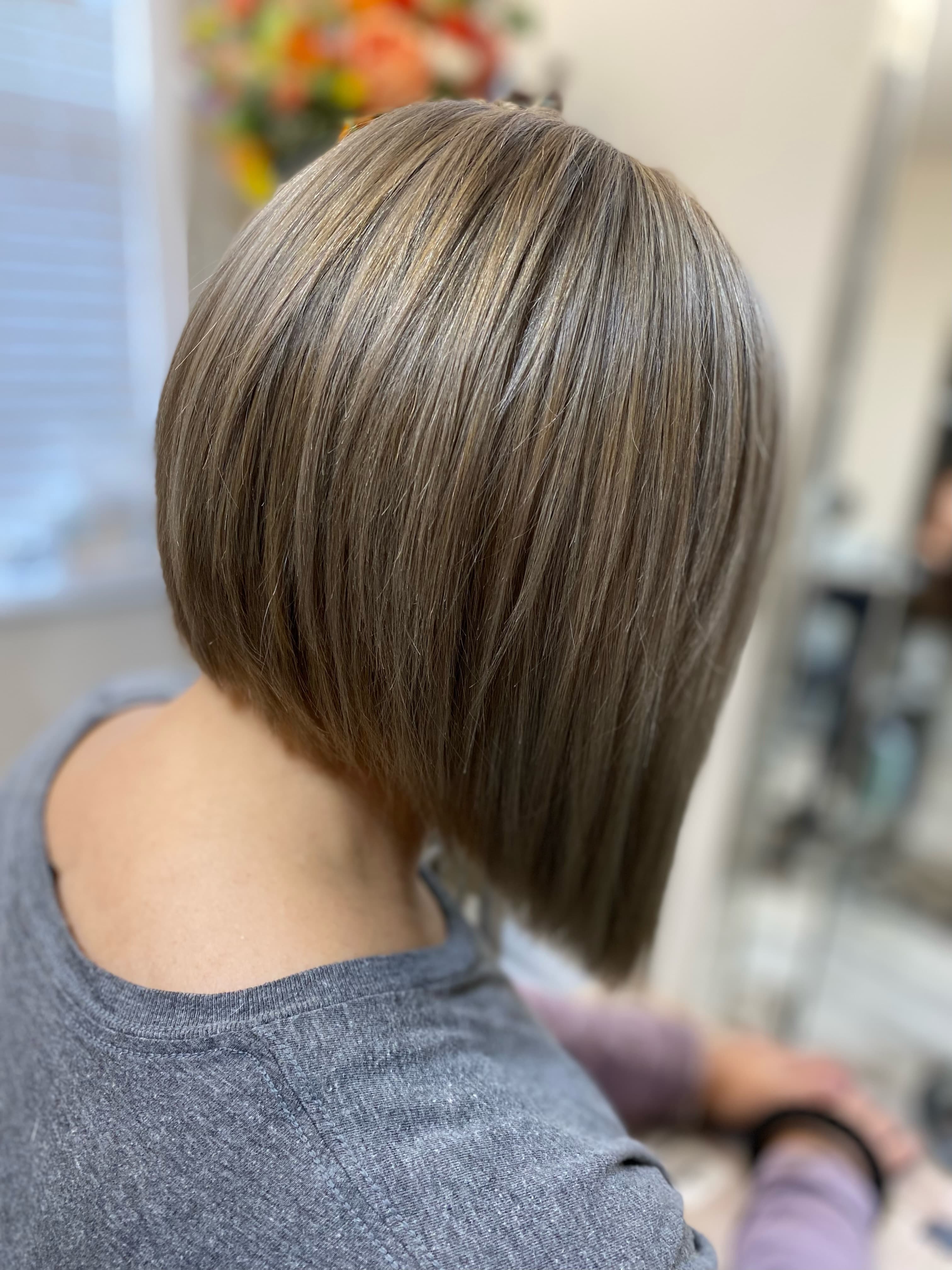 Precision stacked bob cut — sleek angled bob with subtle ash-toned highlights on medium brunette hair, back view at Divine Retreat salon